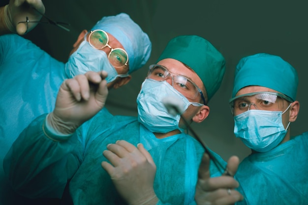 Grupo de cirurgiões trabalhando na sala de cirurgia em tons de azul Equipe médica realizando operação