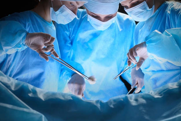 Grupo de cirurgiões trabalhando na sala de cirurgia em tons de azul
