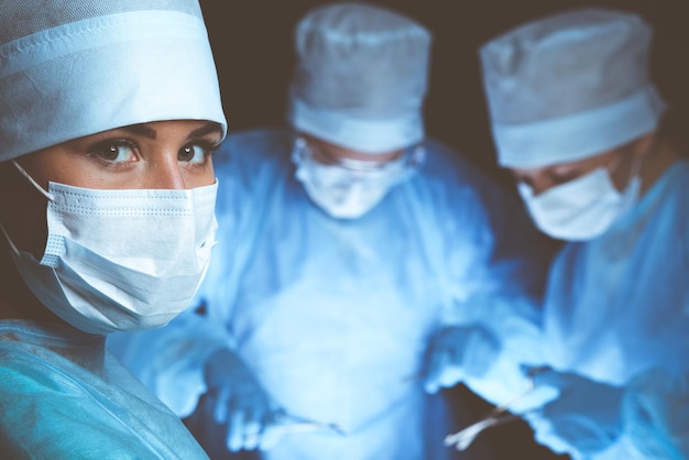 Grupo de cirurgiões usando máscaras de segurança realizando operação. conceito de medicina.