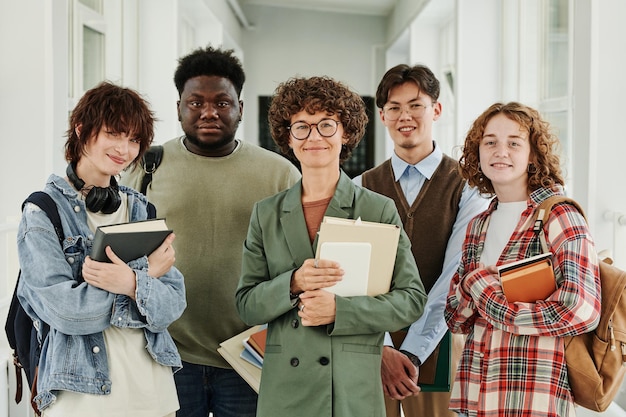 Grupo de colegas adolescentes felizes e seu professor em roupas casuais segurando livros