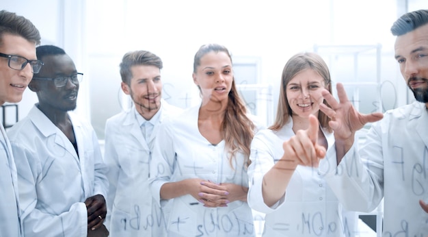 Grupo de colegas concentrados em jalecos brancos discutindo trabalho em laboratório