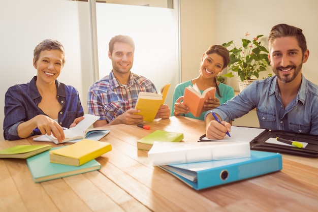 Foto grupo de colegas lendo livros e sorrindo para a câmera