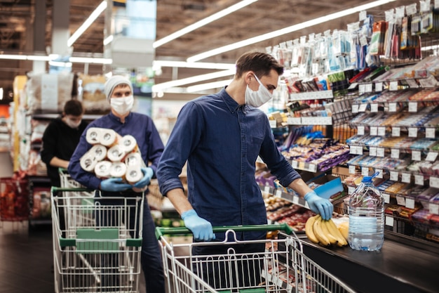 Grupo de compradores com máscaras protetoras em pé perto da caixa de um supermercado. higiene e cuidados de saúde