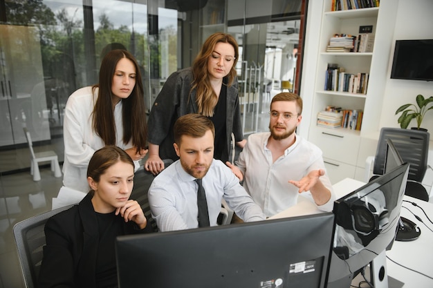 Grupo de corretores da bolsa de empresários e empresárias trabalhando no escritório.