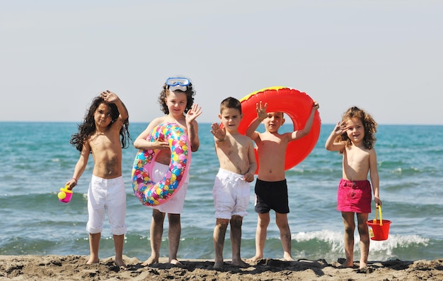 grupo de criança feliz se diverte na praia enquanto brinca com brinquedos correndo pulando