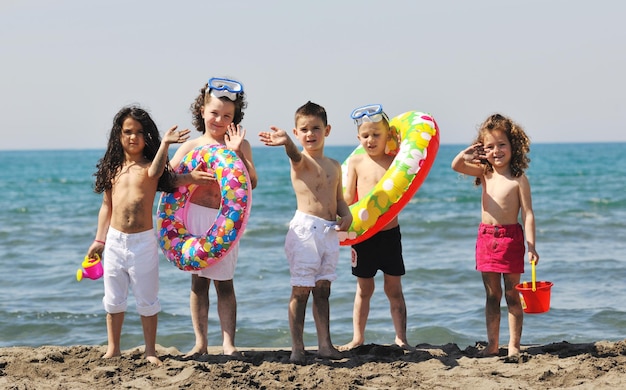 grupo de criança feliz se diverte na praia enquanto brinca com brinquedos correndo pulando