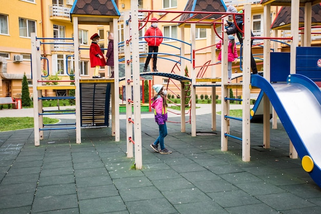 Grupo de crianças anda no playground com máscaras protetoras