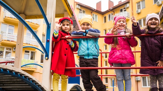 Grupo de crianças andando no playground no tempo frio crianças vestidas com jaquetas e chapéus na primavera