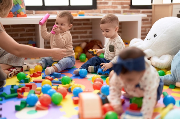 Grupo de crianças brincando com brinquedos sentados no chão no jardim de infância