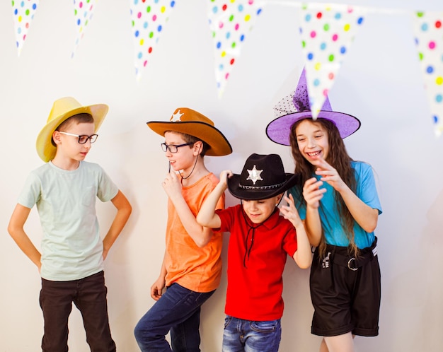 Grupo de crianças celebram a festa de aniversário amigos em trajes festivos e chapéus se divertindo juntos infância feliz