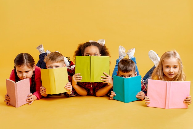 Grupo de crianças cobrindo o rosto com livros