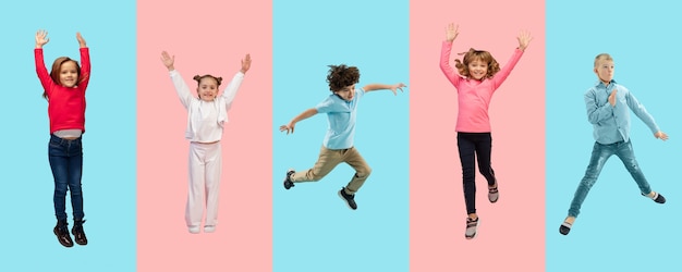 Foto grupo de crianças do ensino fundamental ou alunos pulando em roupas casuais coloridas em estúdio bicolor