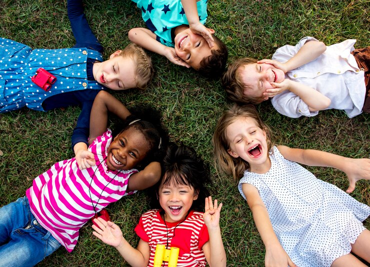 Foto grupo de crianças do jardim de infância deitado na grama no parque e relaxar com o sorriso