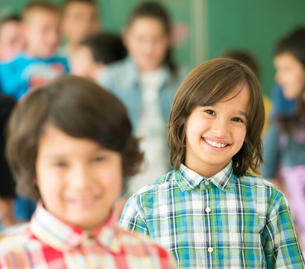 Grupo de crianças felizes com os braços estendidos na sala de aula da escola