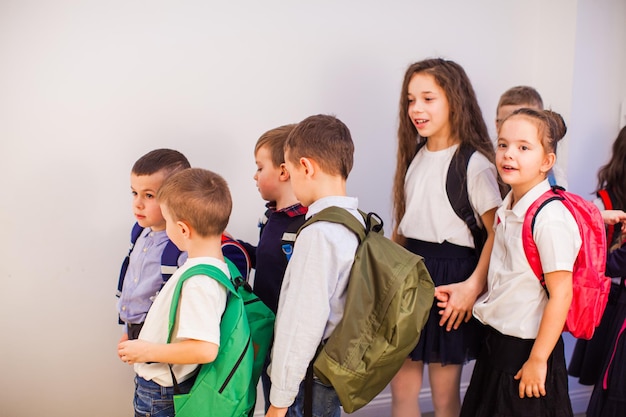 Grupo de crianças felizes da escola na escola Crianças de uniforme com mochilas no corredor da escola