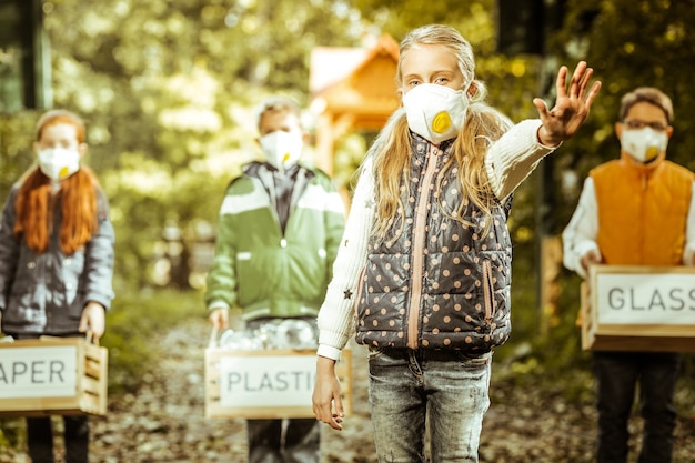 Grupo de crianças segurando caixas de lixo classificado, aumentando a conscientização para a proteção do planeta em um dia bom