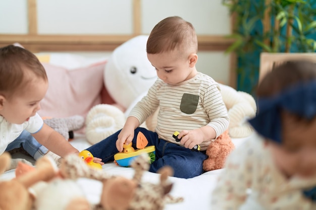 Grupo de crianças sentadas na cama brincando com brinquedos no jardim de infância