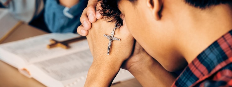 Foto grupo de cristãos oram a deus enquanto seguram a cruz de ferro em close-up