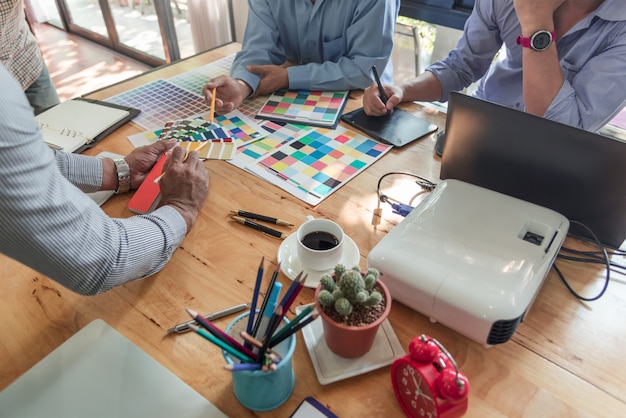 Grupo de designers asiáticos de brainstorming trabalhando em conjunto com colegas e amostras de cores