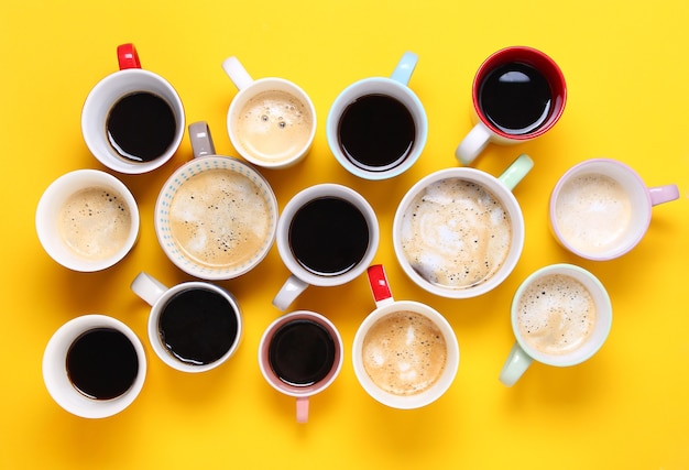 Foto grupo de diferentes xícaras de café em fundo amarelo. vista superior, configuração plana, copie o espaço.