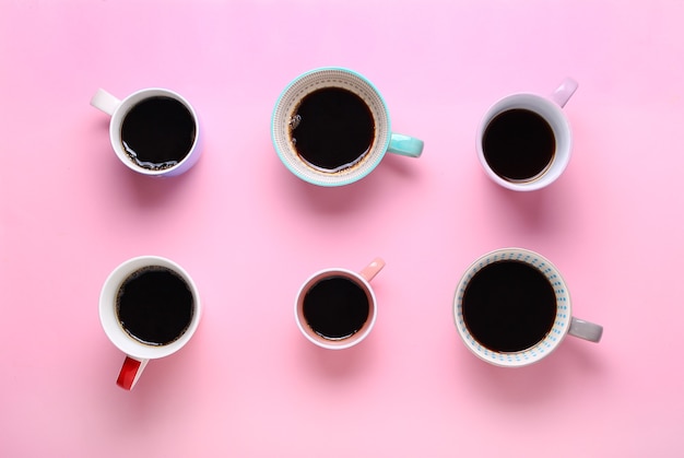 Foto grupo de diferentes xícaras de café no fundo rosa.