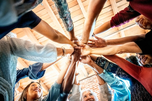 Grupo de diversas pessoas empilhando as mãos no meio