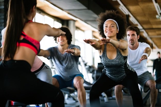 Grupo de diversidade de pessoas treinando em uma academia. Treinador e pessoas em boa forma física se exercitando em uma aula de ginástica