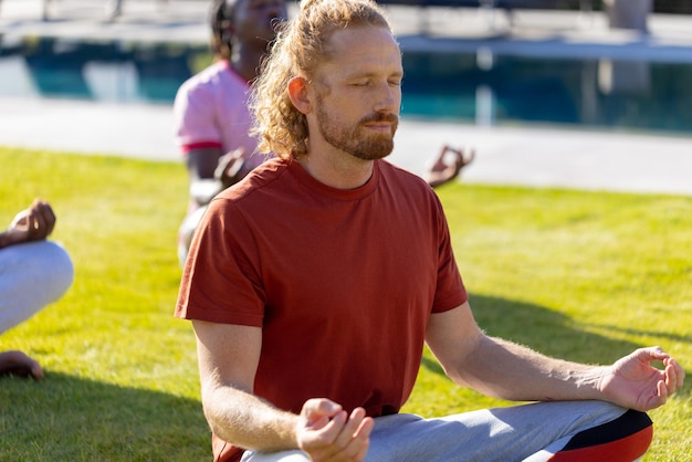 Grupo de diversos amigos fazendo ioga e meditando no jardim