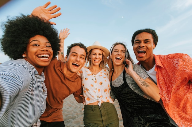 Foto grupo de diversos amigos tomando uma selfie na praia