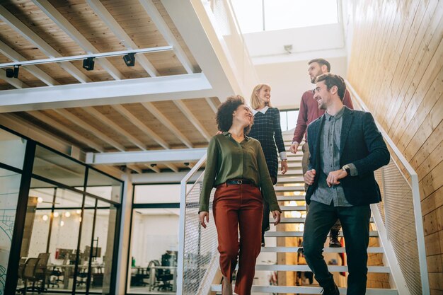 Grupo de diversos colegas de trabalho descendo as escadas em um escritório