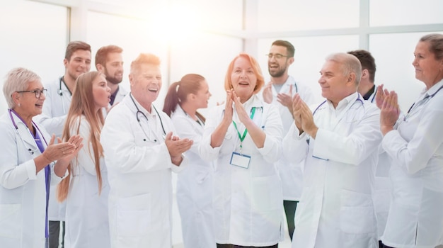 Grupo de diversos médicos sorridentes aplaudindo juntos.