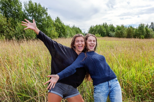 Grupo de duas irmãs amigas dançando, abraçando e se divertindo juntas na natureza ao ar livre