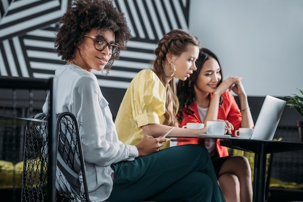 Foto grupo de empresárias multiétnicas a trabalhar juntas num café