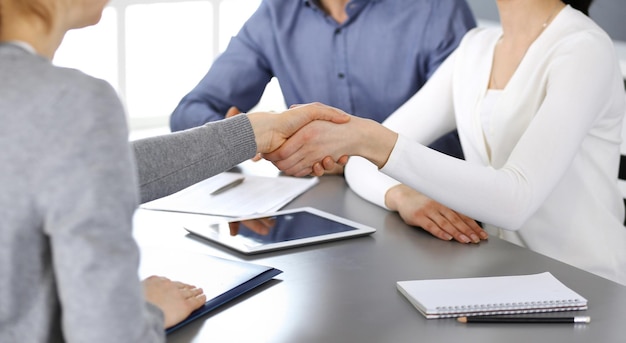 Grupo de empresários apertando as mãos depois de discutir questões e chegar a um acordo na reunião no escritório moderno. Close de aperto de mão. Trabalho em equipe, parceria e conceito de negócios.