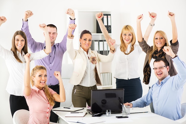 Grupo de empresários bem sucedidos felizes com os braços levantados, olhando para a câmera.