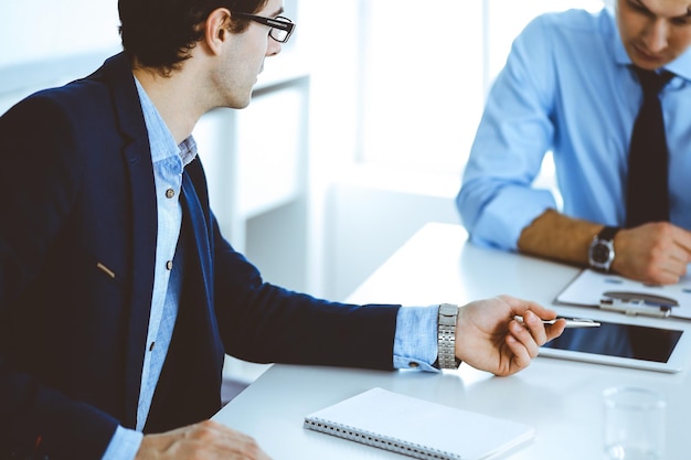 Grupo de empresários discutindo perguntas na reunião no escritório moderno. Gerentes em negociação ou brainstorm. Trabalho em equipe, parceria e conceito de negócios