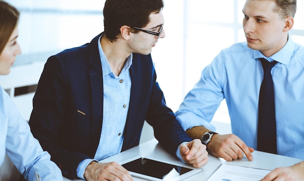 Grupo de empresários discutindo perguntas na reunião no escritório moderno. Gerentes em negociação ou brainstorm. Trabalho em equipe, parceria e conceito de negócios