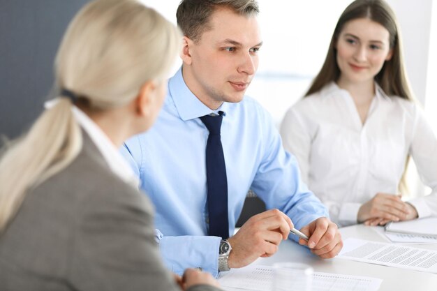 Grupo de empresários discutindo perguntas na reunião no escritório moderno. Gerentes em negociação ou brainstorm. Trabalho em equipe, parceria e conceito de negócios