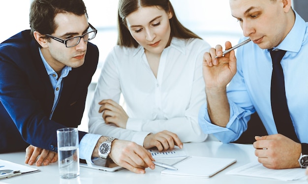 Grupo de empresários discutindo perguntas na reunião no escritório moderno. Gerentes em negociação ou brainstorm. Trabalho em equipe, parceria e conceito de negócios