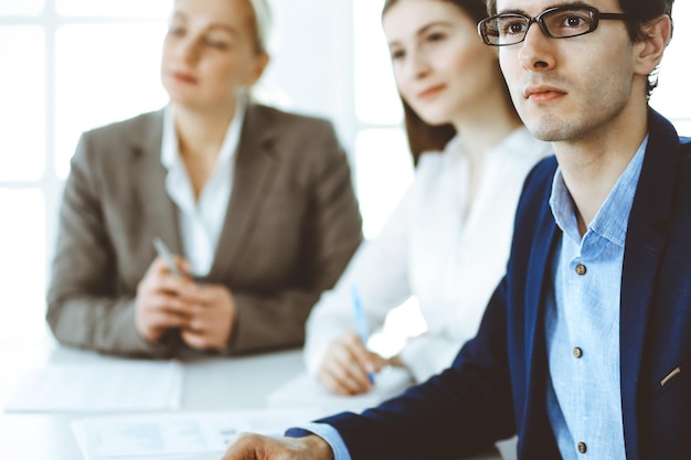 Grupo de empresários discutindo perguntas na reunião no escritório moderno. Tiro na cabeça do empresário na negociação. Trabalho em equipe, parceria e conceito de negócios.