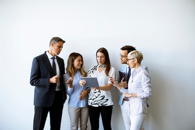Grupo de empresários em pé junto à parede olhando para um tablet digital no escritório