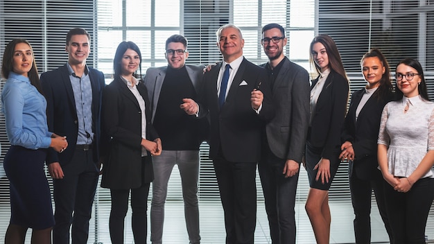 Foto grupo de empresários felizes em pé no saguão do escritório. o conceito de trabalho de sucesso