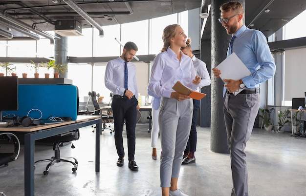 Grupo de empresários modernos estão falando e sorrindo enquanto estão no corredor do escritório