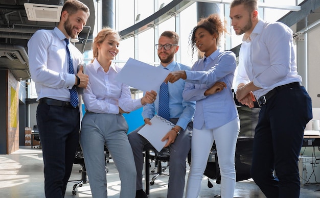 Grupo de empresários modernos estão falando e sorrindo enquanto estão no escritório