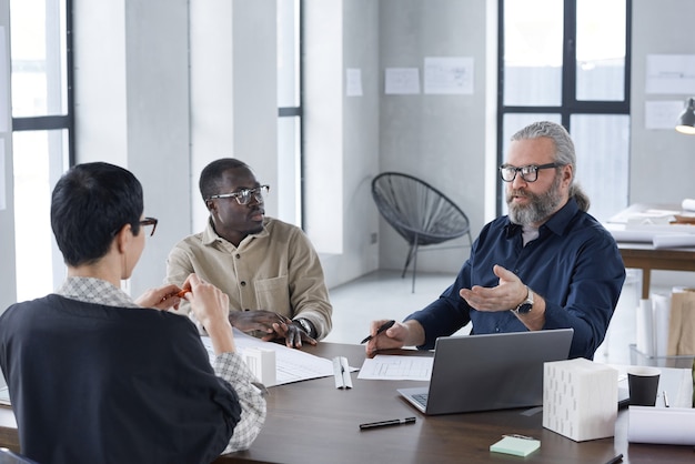 Grupo de empresários sentados à mesa e discutindo em equipe durante uma reunião no escritório