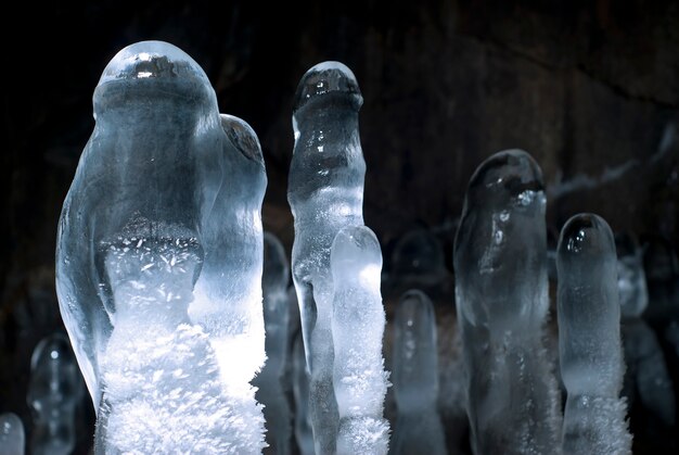 Grupo de estalagmites de gelo transparentes em uma caverna em um fundo escuro