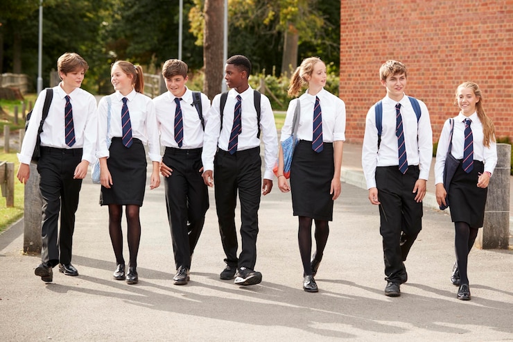 Foto grupo de estudantes adolescentes em uniforme do lado de fora dos edifícios escolares