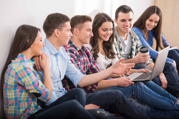 Grupo de estudantes com laptop estão assistindo a algo.