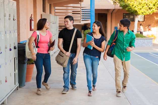 Grupo de estudantes do ensino médio conversando e rindo em um corredor entre as aulas