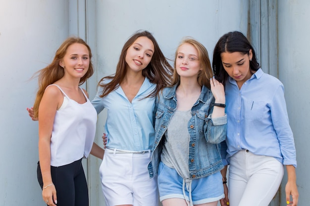 Foto grupo de estudantes do sexo feminino em roupas de verão posando juntos ao ar livre e olhando para a câmera. retrato da moda de namoradas de jovens estudantes. estilo de vida, juventude, pessoas, estilo de vida, conceito de amizade